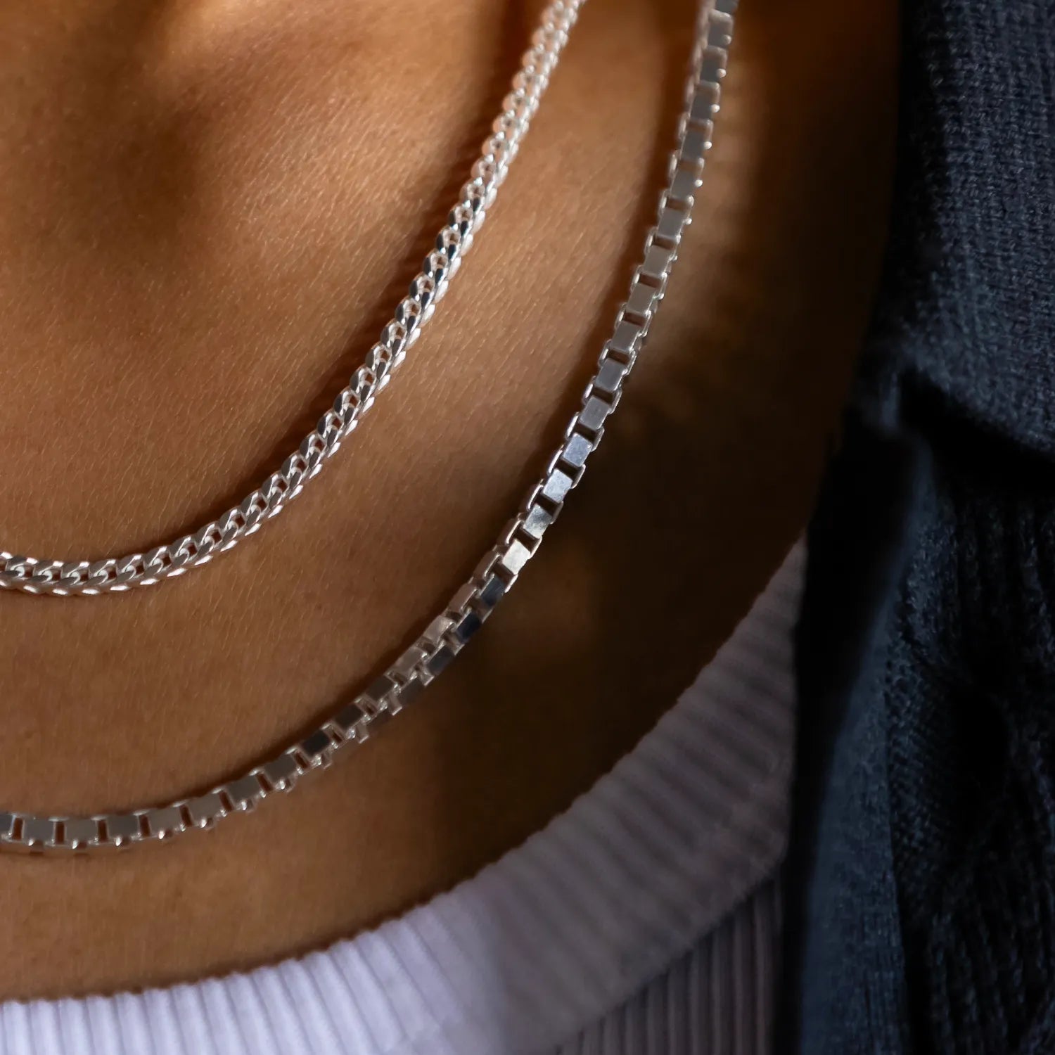 close up of 18" 925 silver franco chain stacked with 20" 925 sterling silver franco chain on a white tank top