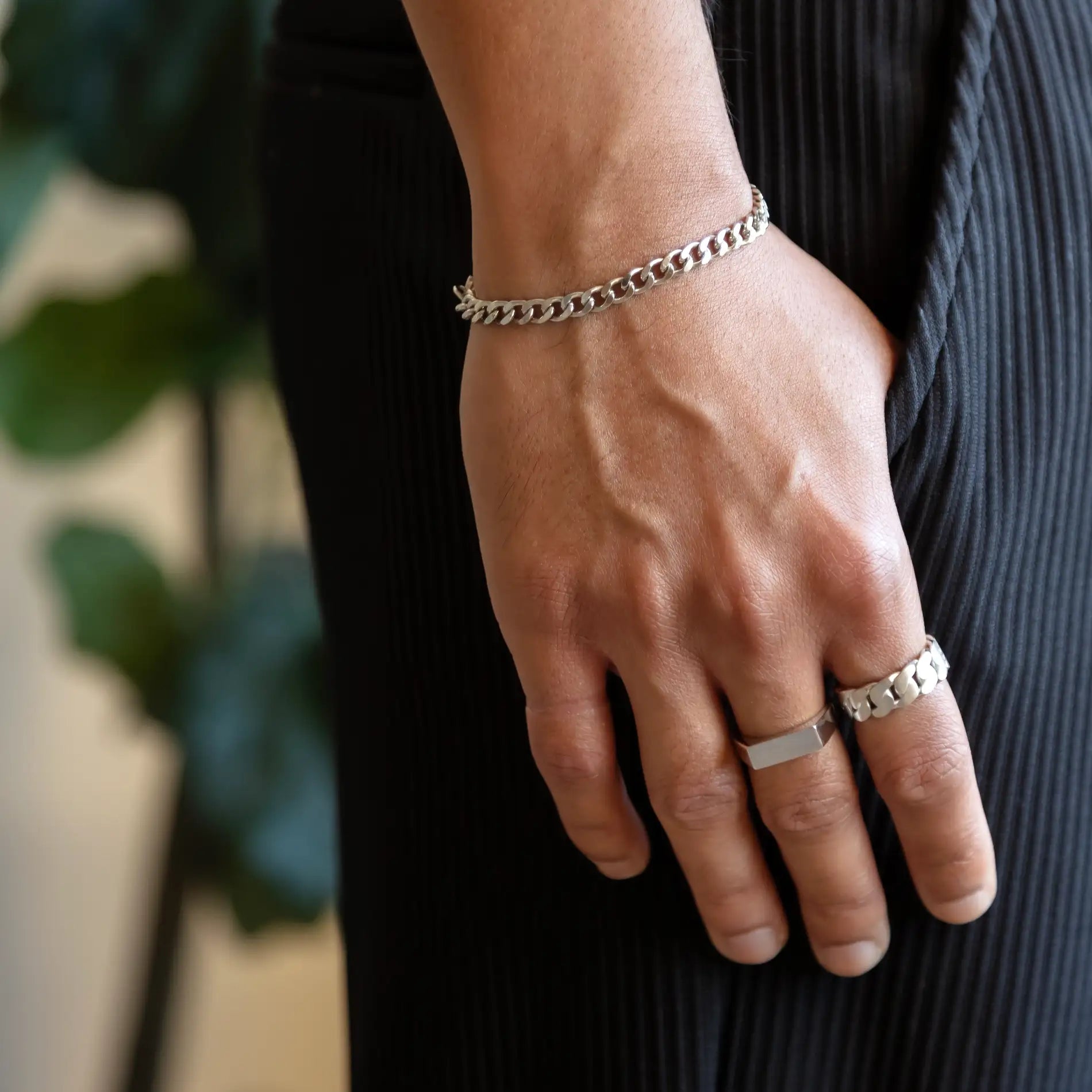 925 silver cuban link bracelet on hand resting on plissé pants