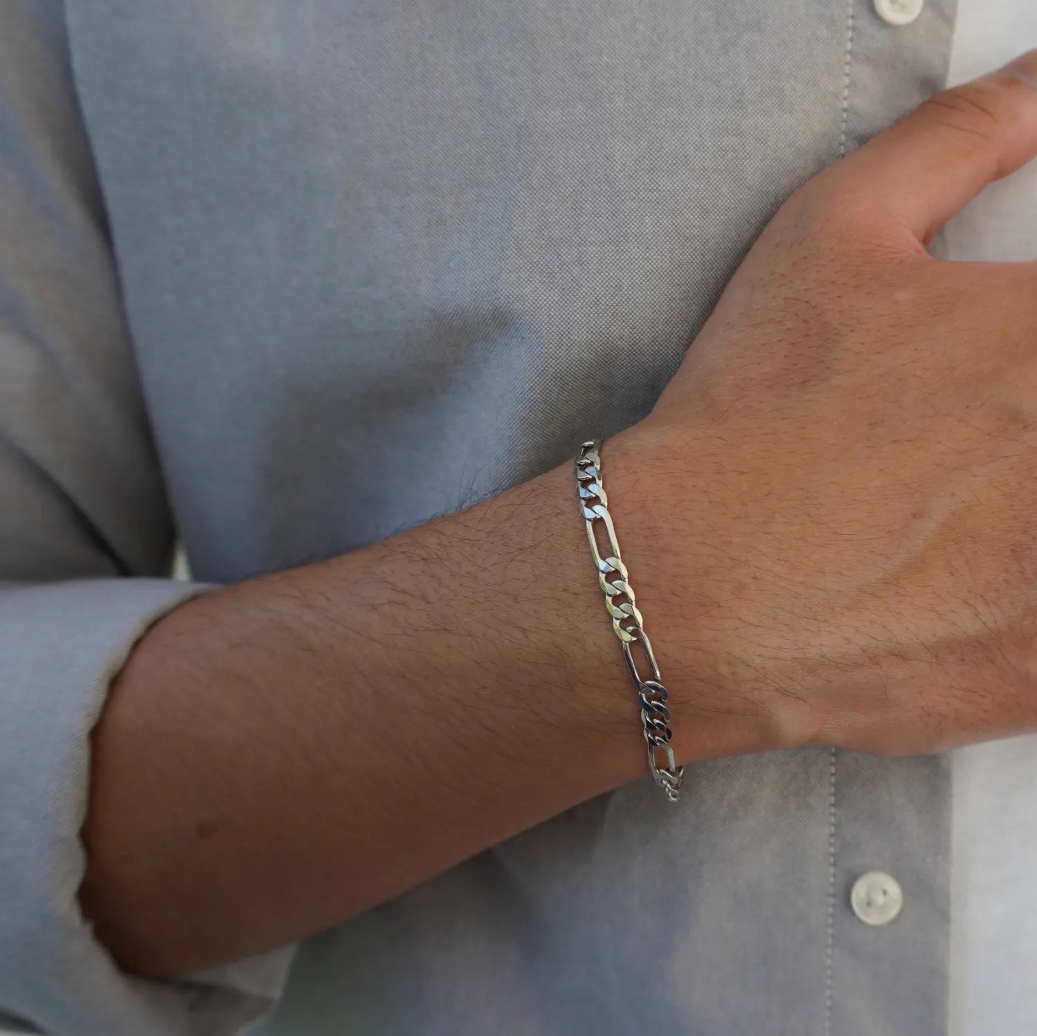 close up of 925 silver figaro chain bracelet on a grey oxford dress shirt